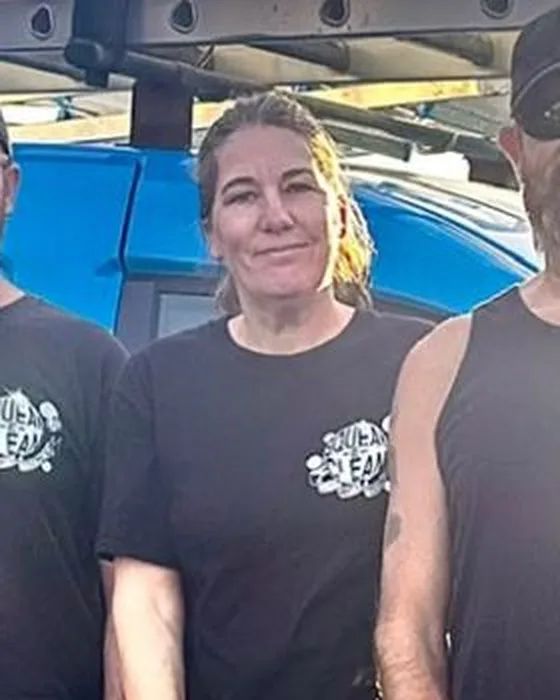 Hayley in a black Squeak-E-Clean T-shirt in front of the blue van
