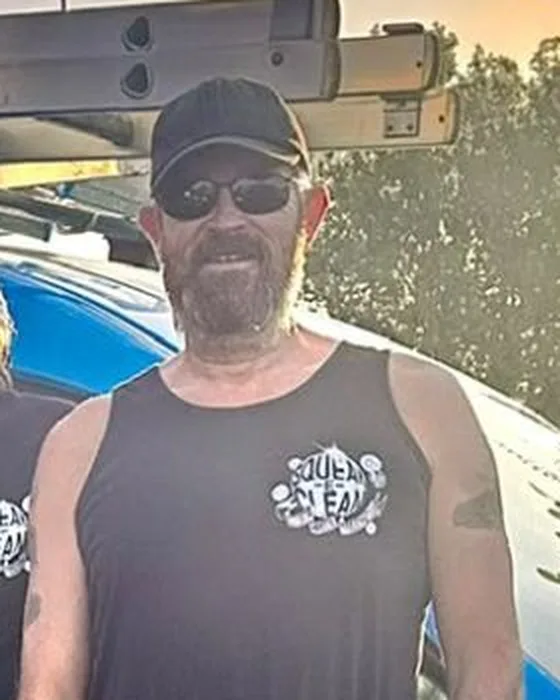 Nick in a black Squeak-E-Clean vest, cap and sunglasses, in front of the blue van